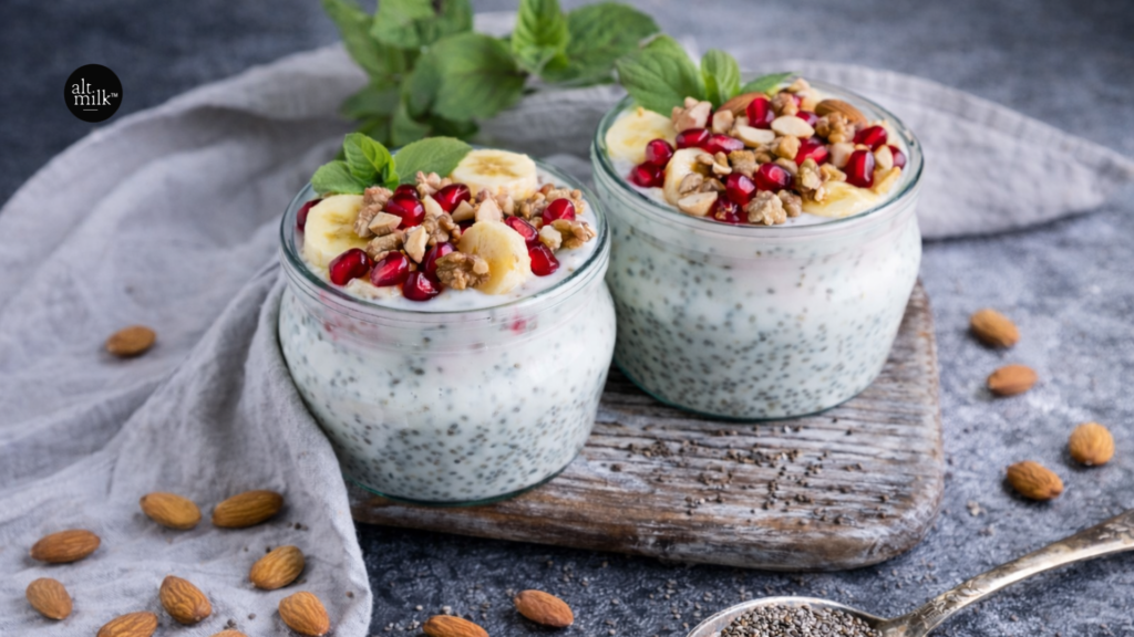 Almond milk chia pudding topped with banana slices, pomegranate seeds, walnuts, and almonds, served in glass jars as a healthy high-protein breakfast or dessert.